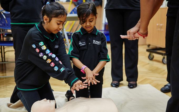 Two young Badger girls practising CPR on a  mannequin. Two young Badger girls practising CPR on a  mannequin.