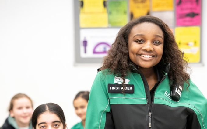Youth Team volunteer stood in front of a Cadet group smiling. Youth Team volunteer stood in front of a Cadet group smiling.