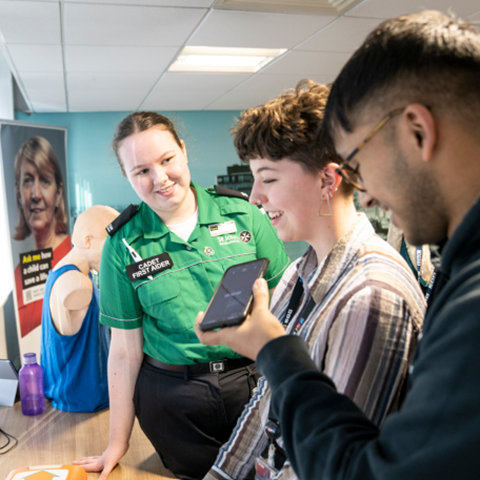 Cadet first aider smiling and talking to two young people.