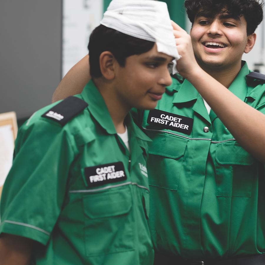 Two Cadet First Aiders practising bandaging their heads.